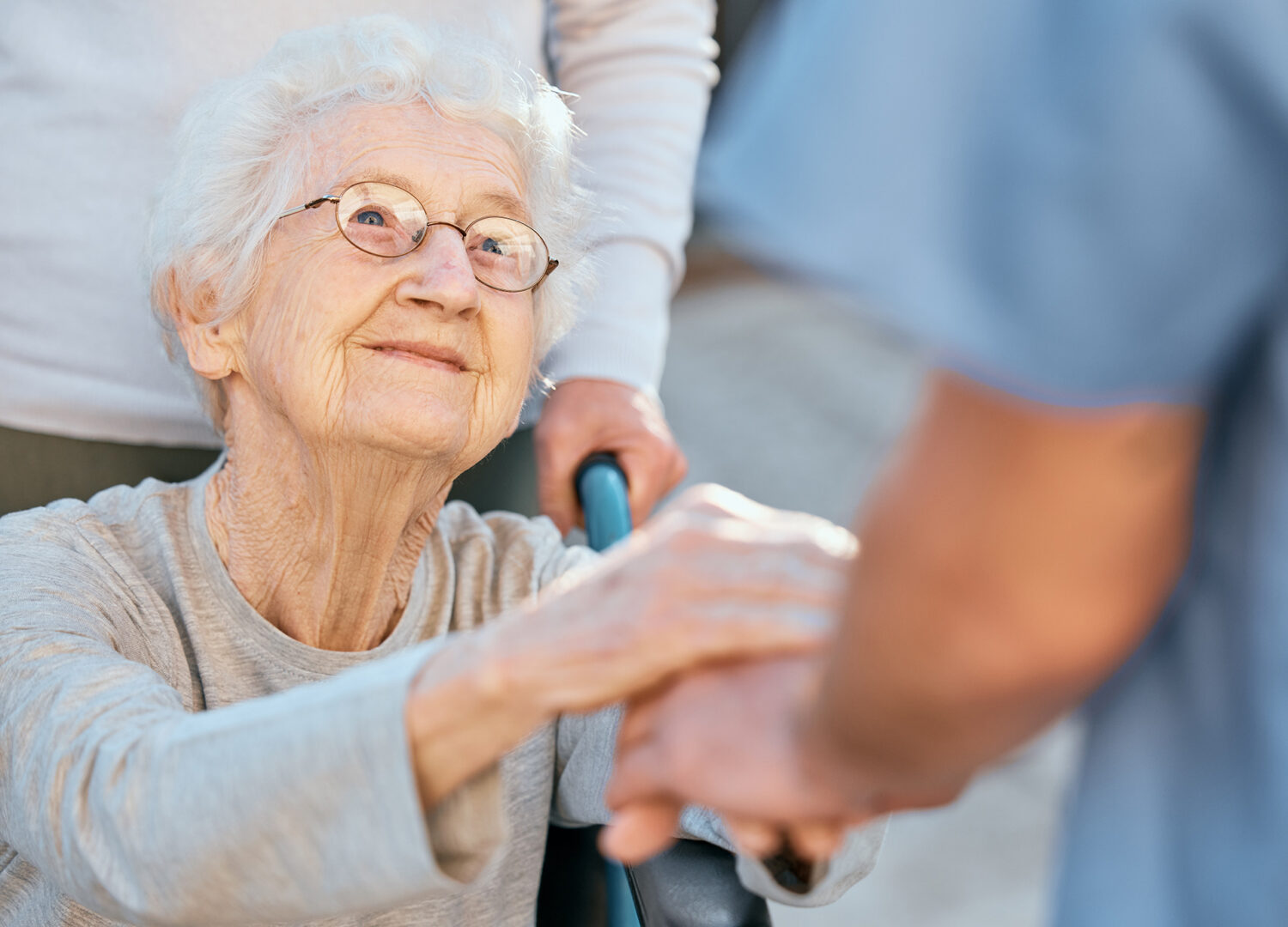 Senior woman looking at her caregiver and holding her hand