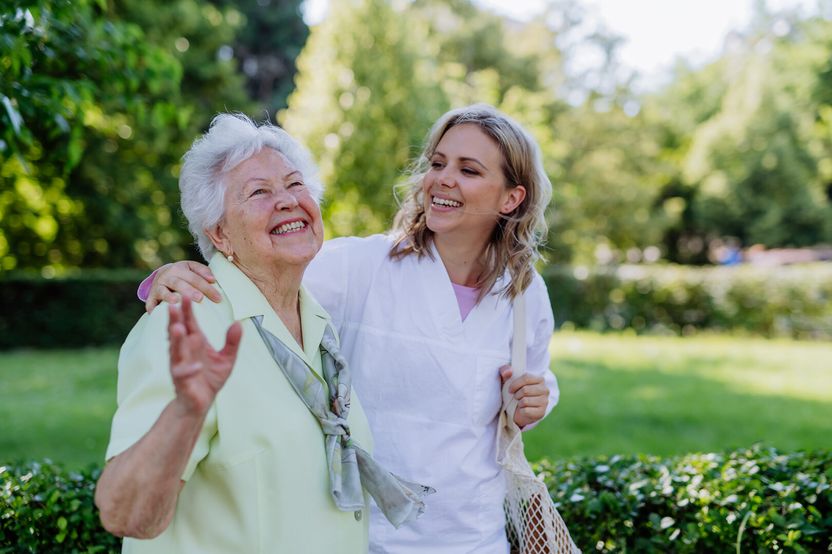 A caregiver and a senior woman walking outside
