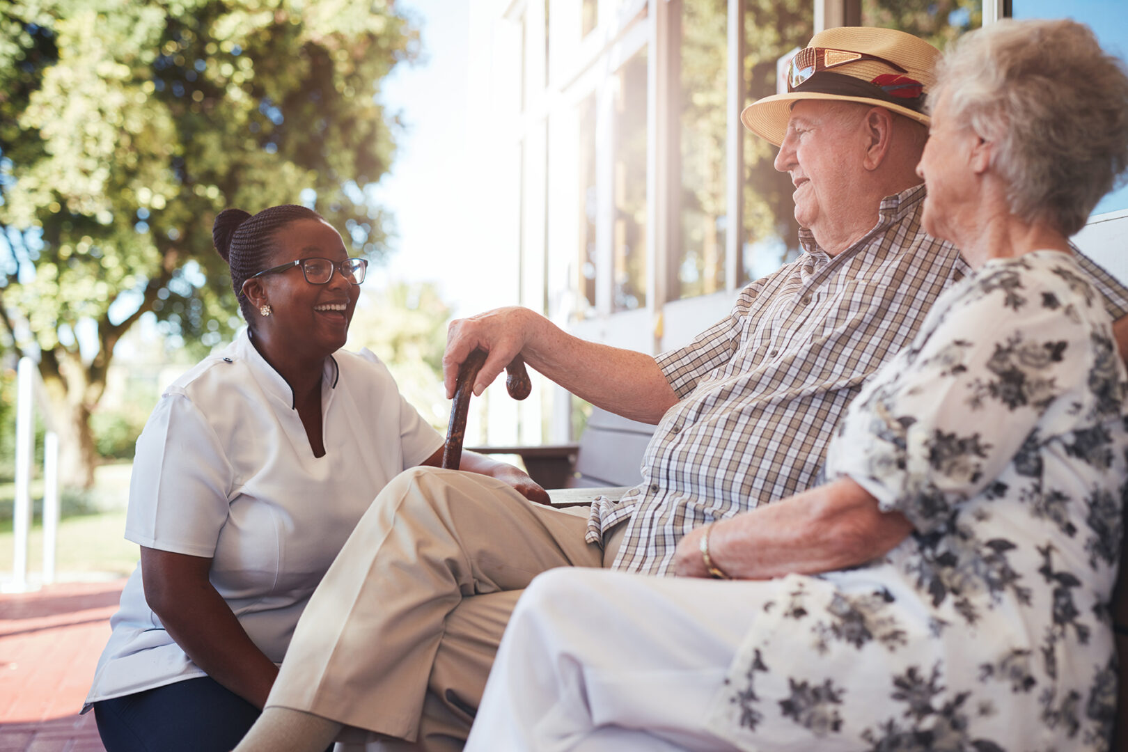 A senior couple with a caregiver sitting outside
